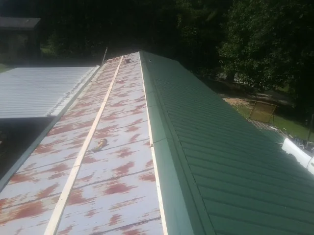 Old rusted panels beside newly installed green metal roofing — Wind Damage Roof Repair by Roofing Brothers in Frenchtown