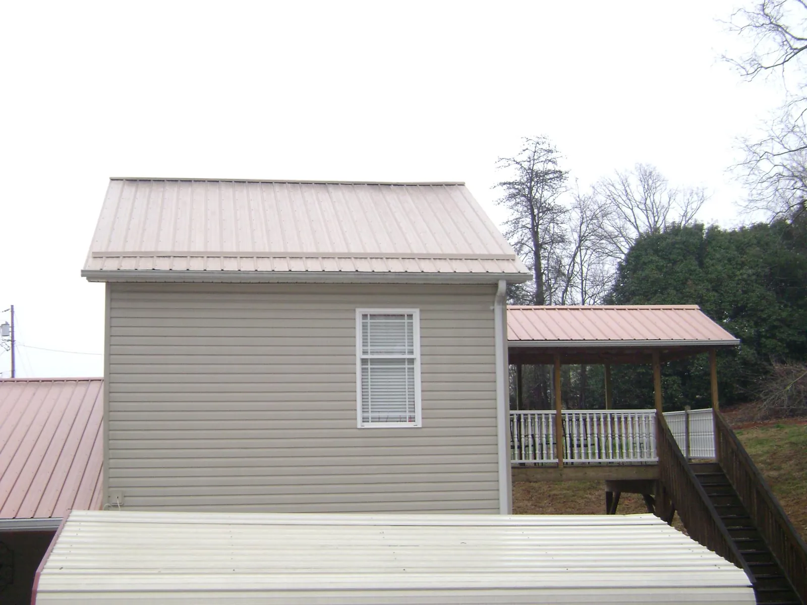 Tan metal roofs on a two story addition and attached porch, from a Roof Replacement job in Frenchtown